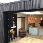 Living room opening onto a garden through glazed doors beneath composite cladding