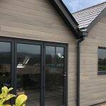 House clad in composite panel cladding with black glazed doors